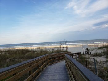 Boardwalk on beach against sky