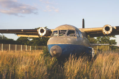 Abandoned airplane on field against sky
