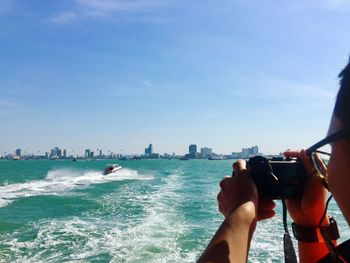 Man holding camera against sea