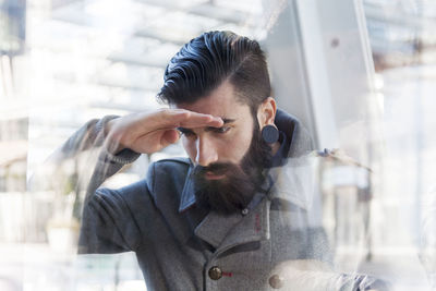 Side view of young man looking through window