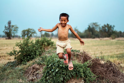 Portrait of happy boy jumping on field