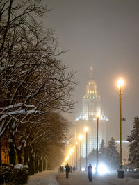 Illuminated street against sky at night