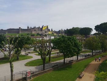 Park by buildings against sky