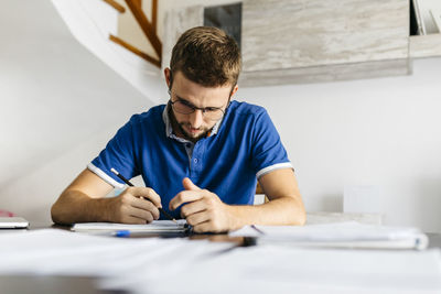 Dedicated young male student doing mathematics homework at table