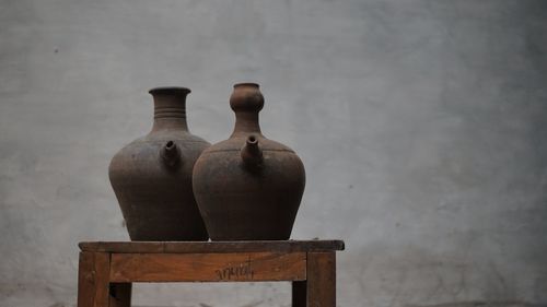 Close-up of vase on table against wall