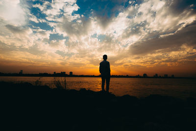 Silhouette man standing on beach against sky during sunset