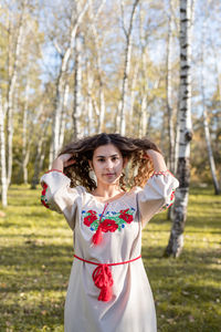 Beautiful woman in national ukrainian national traditional costume clothes walking in forest