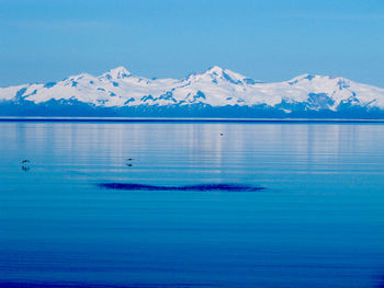 Scenic view of sea and mountains against blue sky