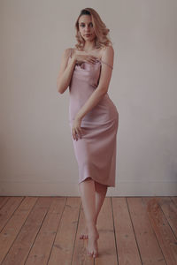 Portrait of young woman standing against wall