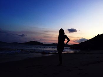 Silhouette woman standing on beach against sky during sunset