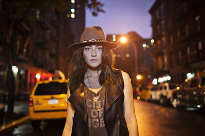 Portrait of beautiful woman standing on street in city at night