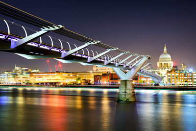 Illuminated bridge over river at night