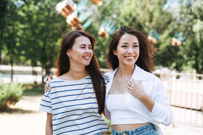 Young women with long hair friends having fun at amusement park