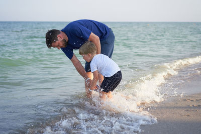 Playful father and son enjoying at beach