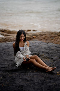 Woman sitting on black sand at beach