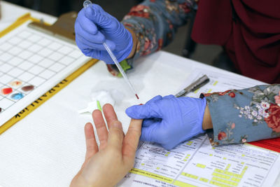 Cropped hands of doctor removing blood sample from patient finger