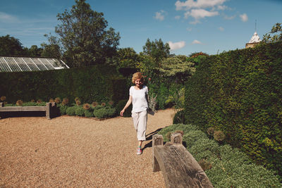 Full length of woman walking by plants in park during summer