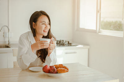 Young woman holding ice cream at home