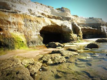 Rock formation on shore against sky