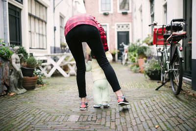 Rear view of woman with baby on alley