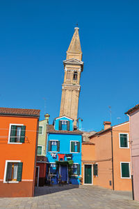 Colorful buildings and leaning bell tower at burano, a little town full of canals in italy.