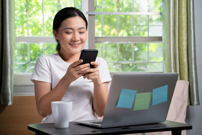 Young woman using phone on table