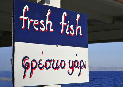 Close-up of warning sign on sea