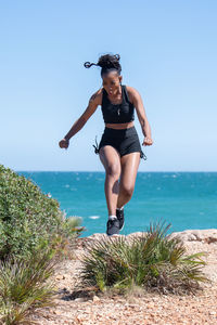 Full length of young woman on sea shore against sky