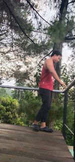 Full length of young man sitting on plant against trees