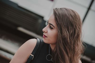 Close-up of young woman looking away in city