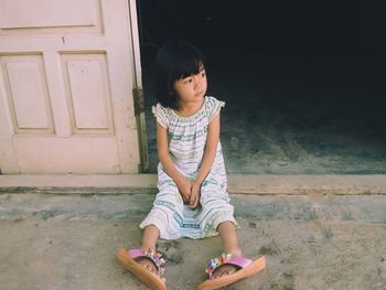 High angle view of thoughtful girl looking away while sitting at doorway