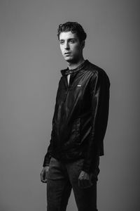 Handsome young man standing against gray background