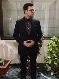 Young man looking away while standing on potted plant