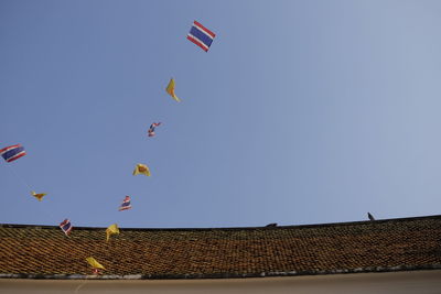 Low angle view of flags hanging from house roof against sky