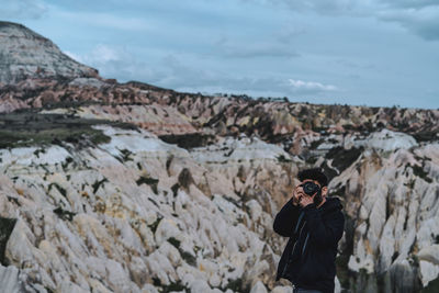 Man photographing while standing against mountains