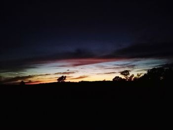 Silhouette landscape against dramatic sky during sunset