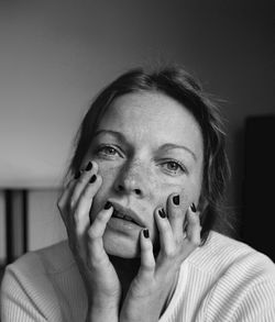 Close-up portrait of woman with hands on chin at home