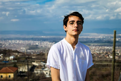 Portrait of young man standing against cityscape