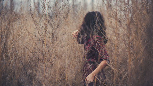 Woman standing by bare tree in forest