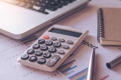 Close-up of laptop and calculator on document in office