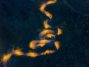 Aerial view of illuminated winding road at dusk