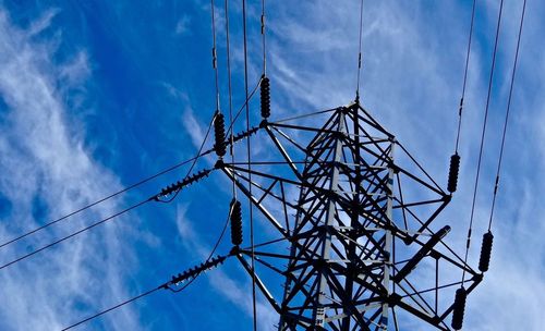 Low angle view of electricity pylon against blue sky