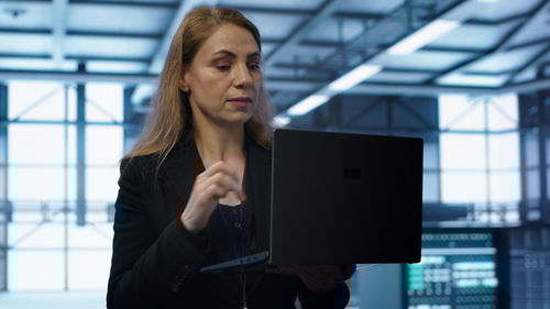 Portrait of young woman using laptop at office
