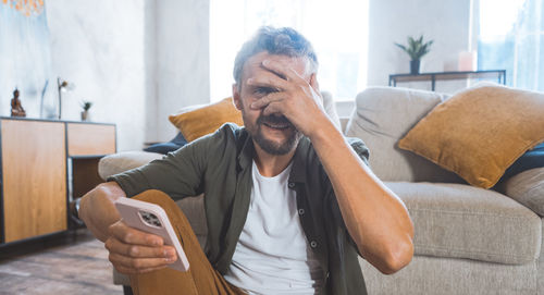 Young woman using mobile phone while sitting on sofa at home