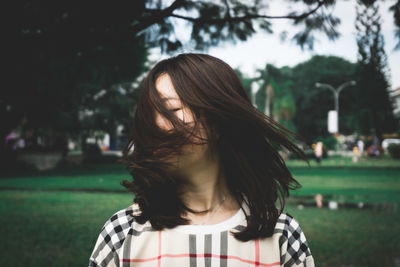Young woman shaking head while standing at park
