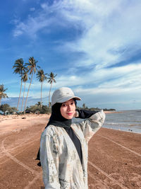 Portrait of woman standing at beach against sky