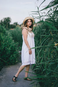 Portrait of young woman standing against plants