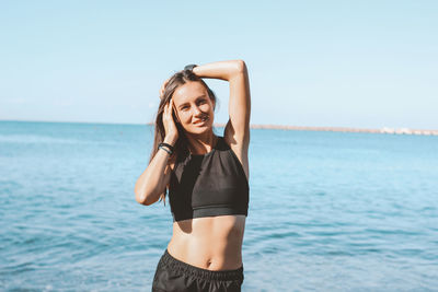 Young woman standing in sea against sky