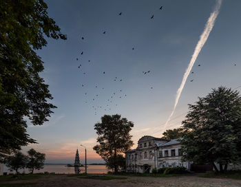 Low angle view of vapor trail and birds flying against sky during sunset