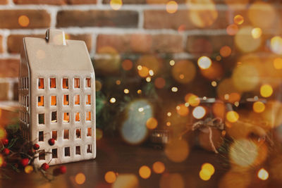 Christmas candle in form of house or home, blurred christmas fir tree lights